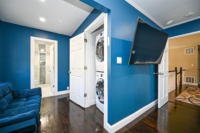 clothes washing area with visible vents, stacked washer / dryer, laundry area, baseboards, and hardwood / wood-style flooring