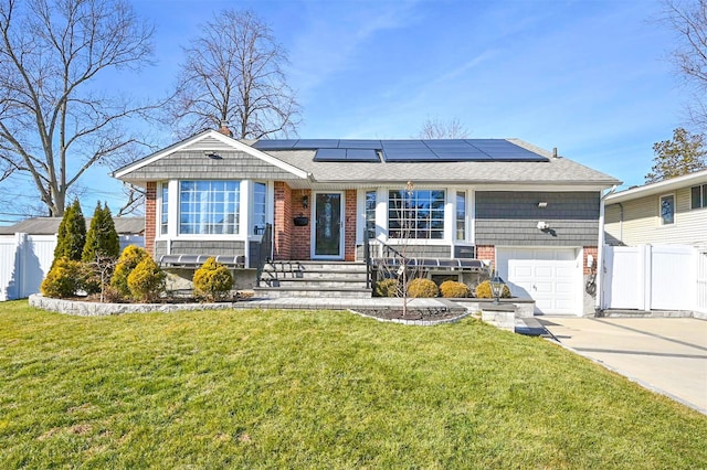 single story home featuring solar panels, concrete driveway, a front yard, and fence