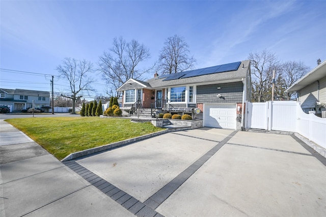 view of front of house featuring solar panels, fence, driveway, a gate, and a front yard