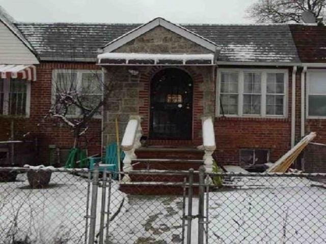 view of front of house featuring roof with shingles, brick siding, a fenced front yard, and a gate