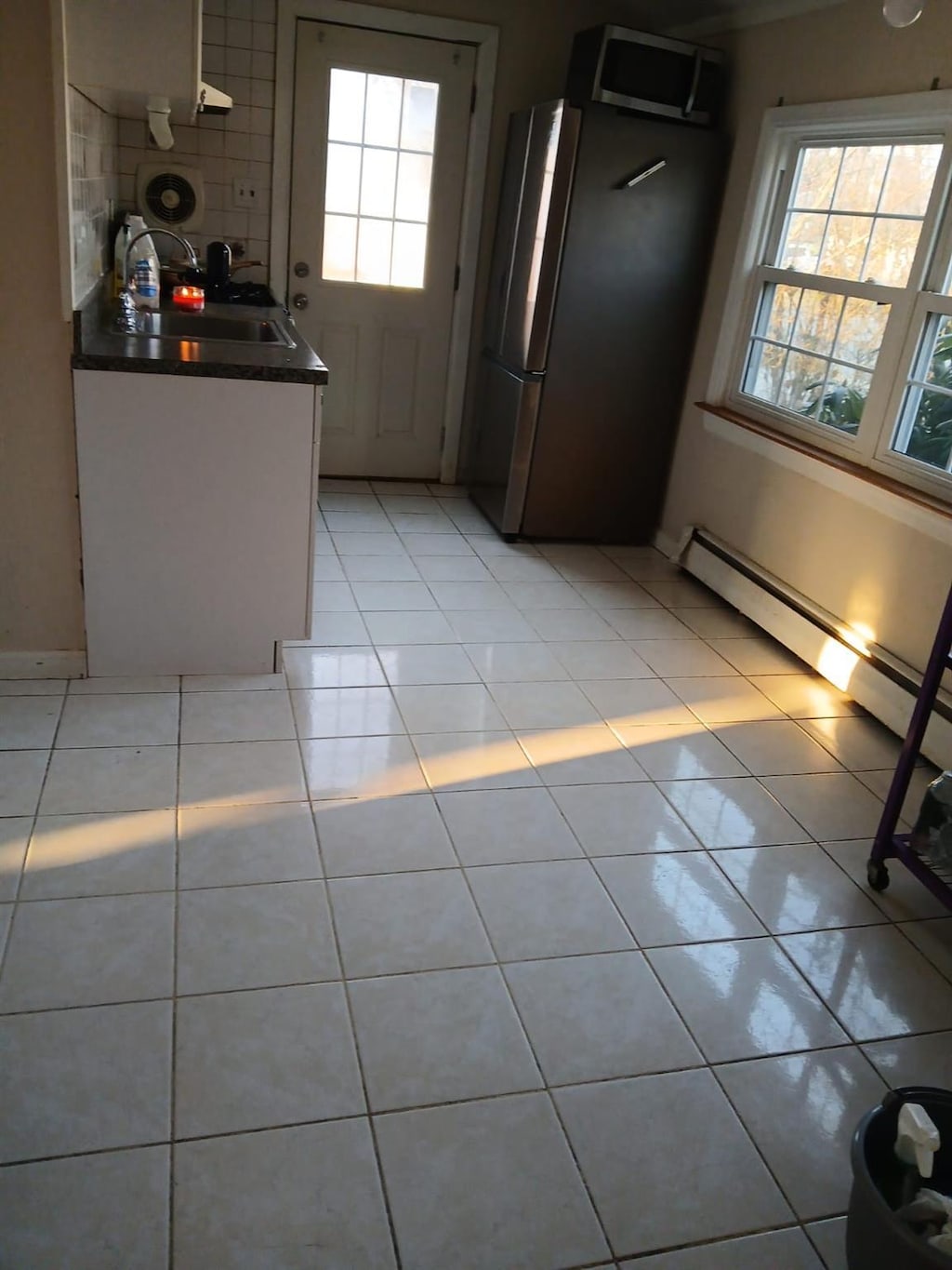 kitchen featuring tasteful backsplash, dark countertops, appliances with stainless steel finishes, light tile patterned flooring, and a sink