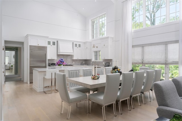 dining room with high vaulted ceiling and light wood-style floors