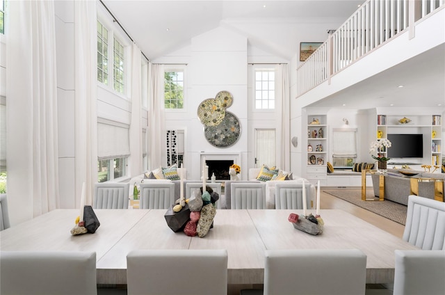 dining space with high vaulted ceiling, built in shelves, and a fireplace