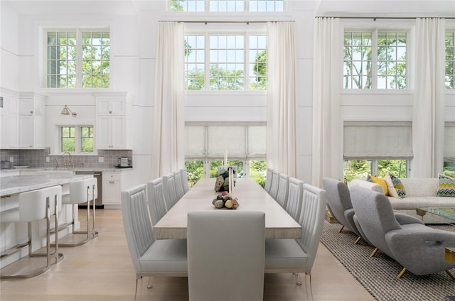 dining area with light wood-style floors and a high ceiling