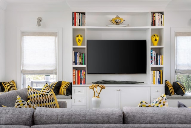 living area featuring built in shelves and crown molding