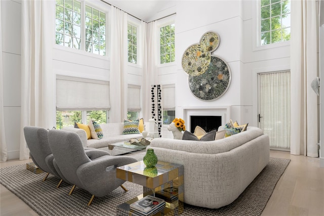 living room with a healthy amount of sunlight, a fireplace, a high ceiling, and wood finished floors