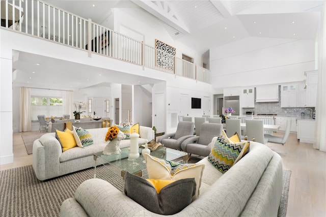 living room with light wood-type flooring, high vaulted ceiling, and beam ceiling