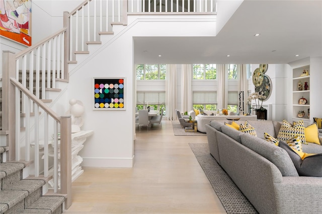 living room featuring baseboards, stairway, wood finished floors, and recessed lighting