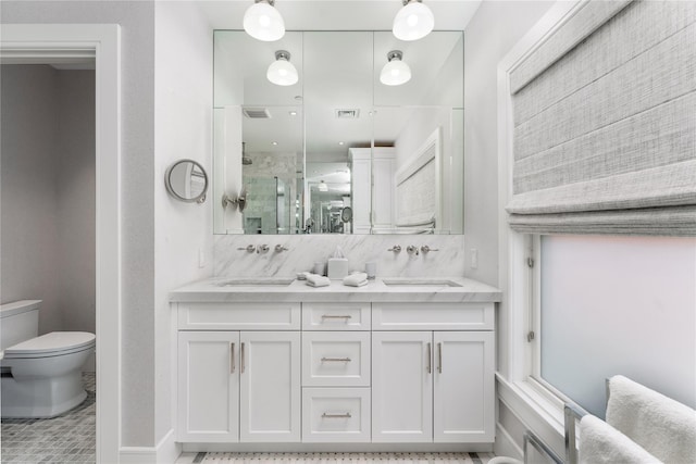 full bath with toilet, a stall shower, double vanity, and a sink