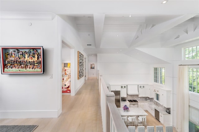 interior space with vaulted ceiling with beams, light wood-style flooring, and baseboards