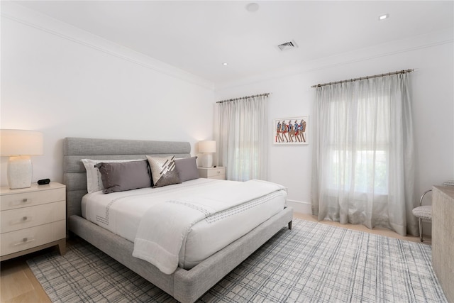 bedroom with visible vents, ornamental molding, and light wood-style flooring