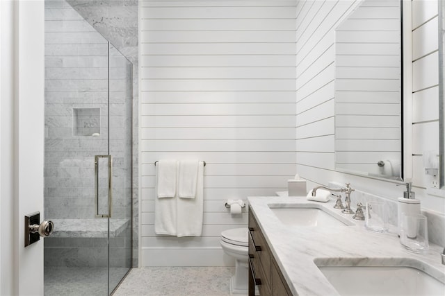 full bath featuring double vanity, a stall shower, wooden walls, toilet, and a sink