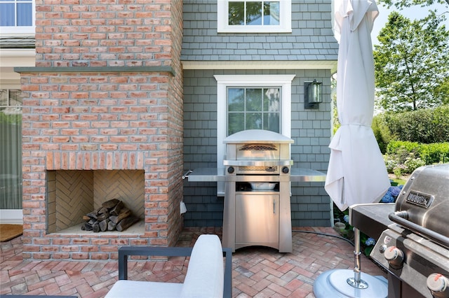 view of patio / terrace featuring an outdoor brick fireplace and grilling area