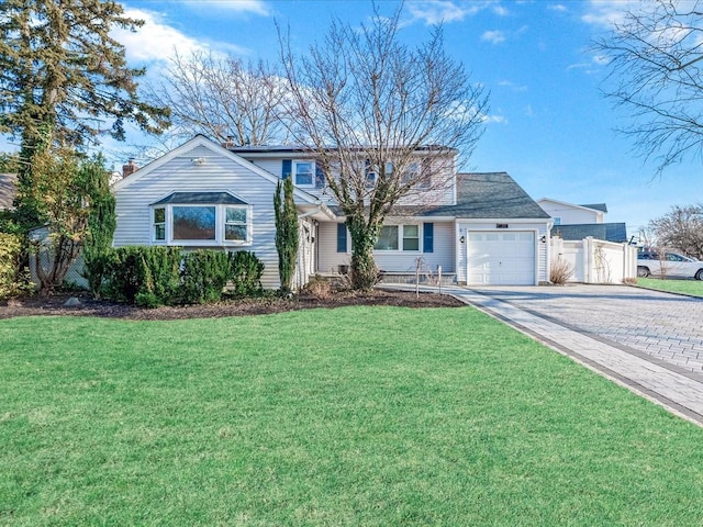 traditional home featuring a garage, fence, a front lawn, and decorative driveway