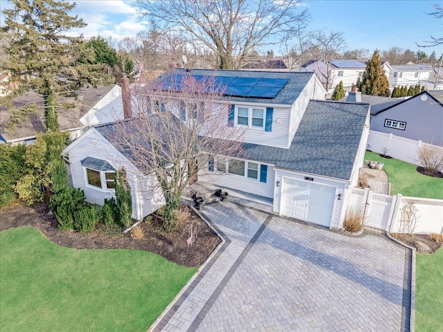 view of front of house featuring roof with shingles, a gate, fence, decorative driveway, and roof mounted solar panels