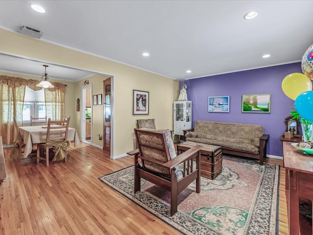 living room featuring baseboards, light wood finished floors, and crown molding