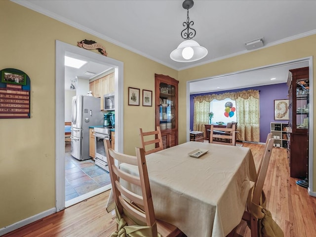 dining area featuring baseboards, ornamental molding, and light wood-style floors