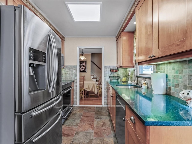 kitchen with brown cabinets, crown molding, decorative backsplash, appliances with stainless steel finishes, and a sink