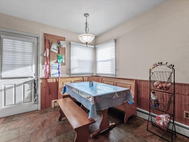 dining area with baseboard heating, stone finish floor, wainscoting, and wood walls