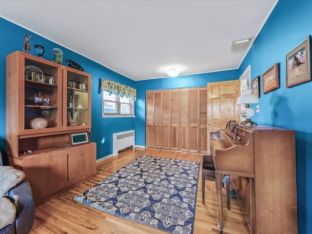 office featuring radiator, baseboards, visible vents, and wood finished floors