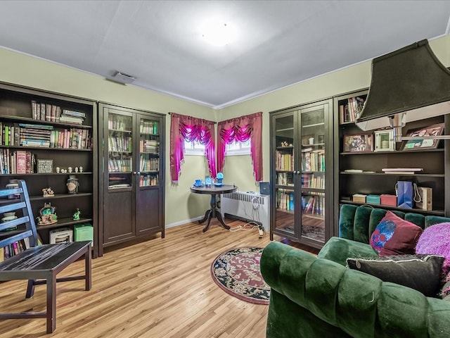 living area with radiator, visible vents, baseboards, and wood finished floors