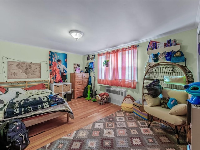 bedroom with radiator heating unit and wood finished floors