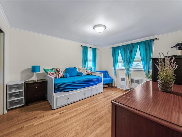 bedroom featuring ornamental molding, radiator heating unit, and wood finished floors