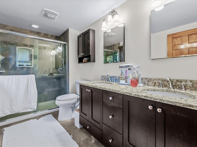 bathroom featuring double vanity, a stall shower, visible vents, and a sink