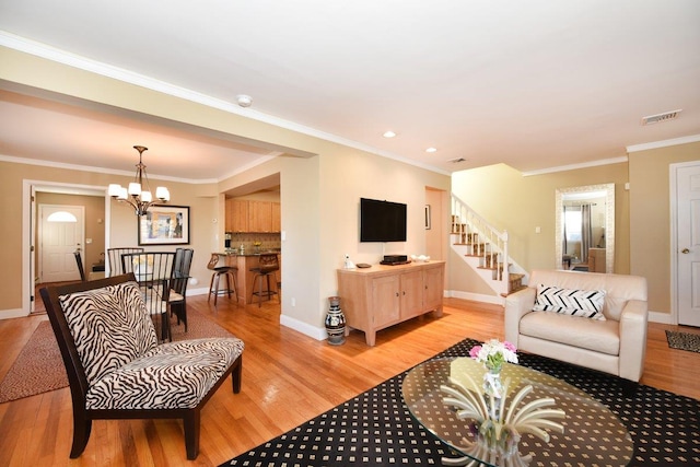 living room with baseboards, visible vents, light wood-style flooring, an inviting chandelier, and crown molding