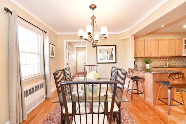 dining room featuring ornamental molding, radiator, a notable chandelier, and light wood-style floors