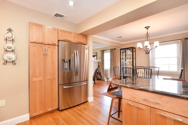 kitchen featuring stainless steel fridge with ice dispenser, light wood-style flooring, a breakfast bar, crown molding, and light brown cabinets