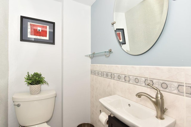 bathroom with toilet, a wainscoted wall, tile walls, and vanity