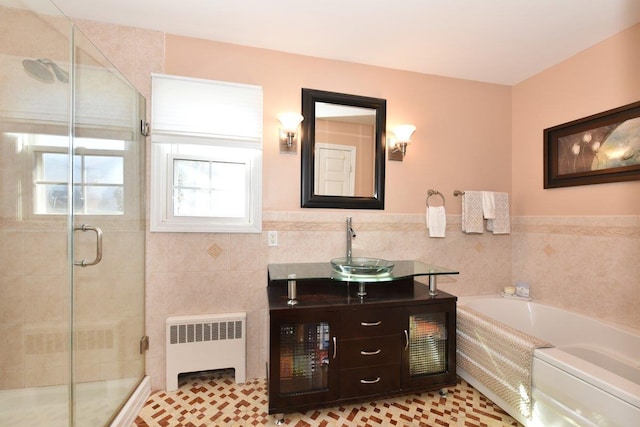 bathroom featuring tile walls, radiator heating unit, vanity, a shower stall, and a bath