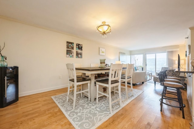 dining area featuring light wood-type flooring, baseboards, and crown molding