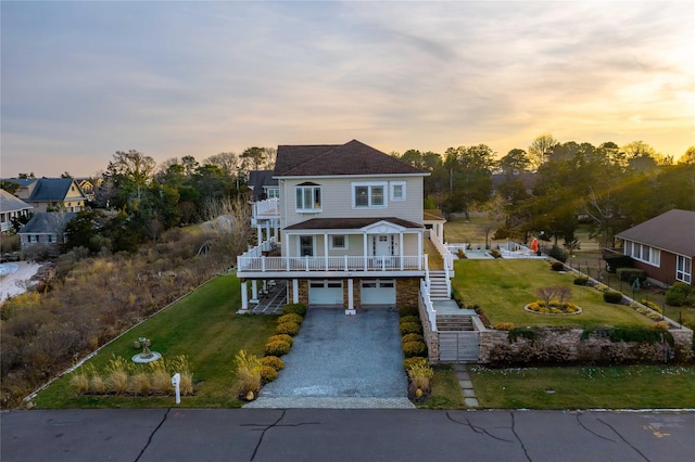 view of front of house with gravel driveway, stairs, and a lawn