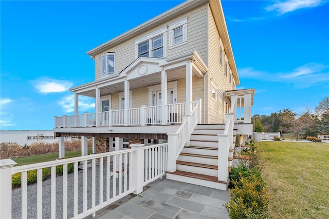 view of front of house featuring covered porch, a front lawn, and stairs