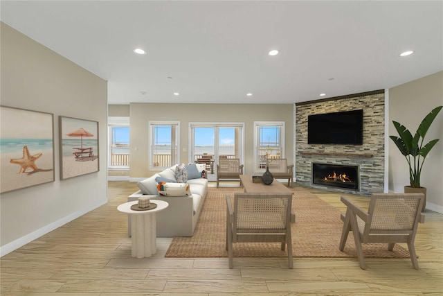 living area with a large fireplace, recessed lighting, baseboards, and light wood-style floors