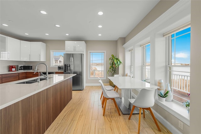 kitchen featuring stainless steel appliances, light countertops, light wood-style floors, a sink, and modern cabinets