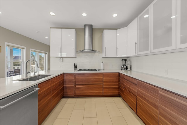 kitchen with appliances with stainless steel finishes, a sink, wall chimney range hood, and modern cabinets