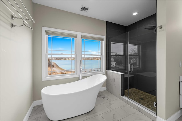 bathroom with marble finish floor, visible vents, a freestanding bath, a shower stall, and baseboards