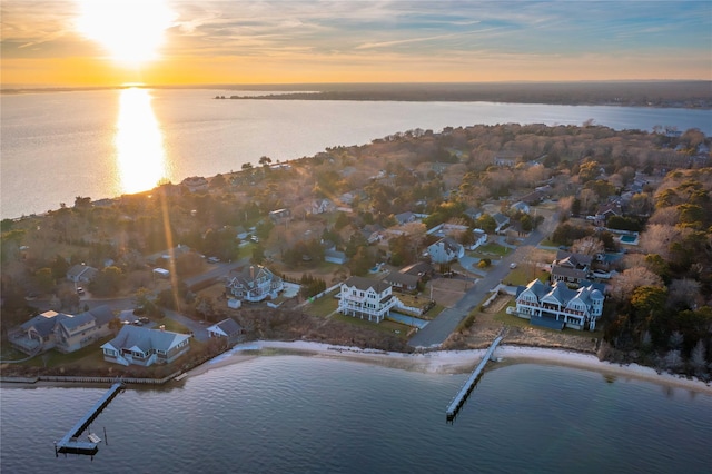 aerial view at dusk with a water view and a residential view