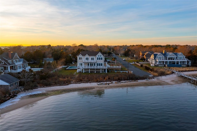 aerial view at dusk featuring a beach view and a water view