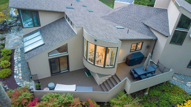 back of property featuring stucco siding, a deck, and a shingled roof