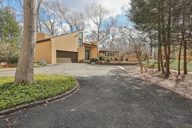 view of property exterior featuring stucco siding, driveway, and a garage