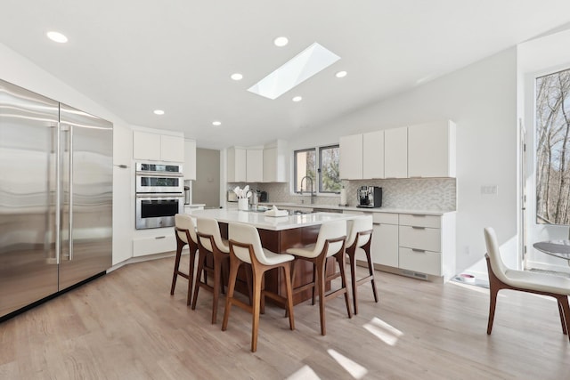 kitchen with a breakfast bar, backsplash, a kitchen island, stainless steel appliances, and light countertops