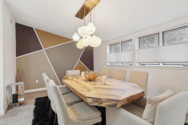 dining room featuring light wood-style floors, baseboards, and a chandelier