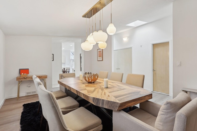 dining area featuring baseboards, visible vents, a skylight, and light wood-style floors