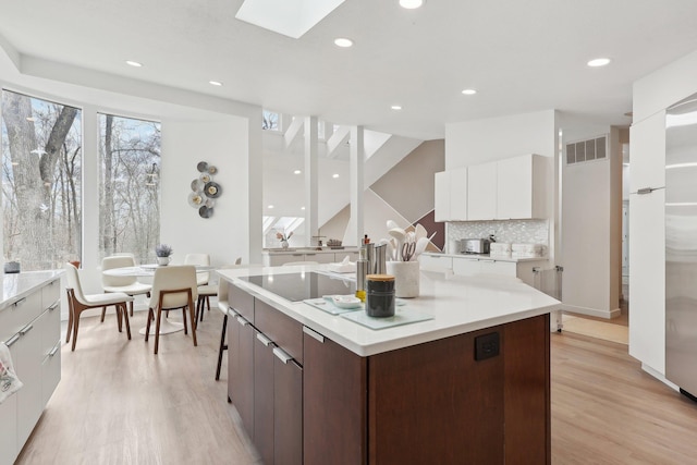 kitchen featuring light wood finished floors, a skylight, white cabinets, modern cabinets, and black electric cooktop