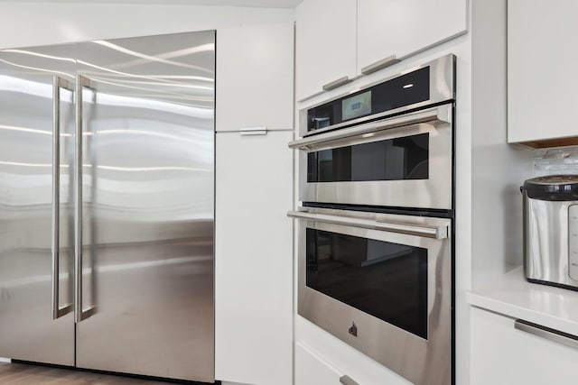 kitchen featuring white cabinets, stainless steel appliances, light countertops, and modern cabinets