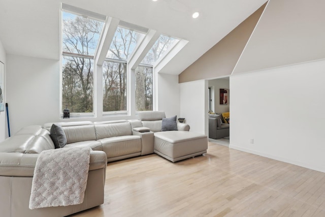 living room with recessed lighting, baseboards, vaulted ceiling with skylight, and light wood-style floors